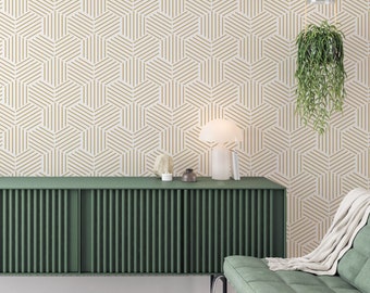 Puede incluir: Un armario verde con una pared blanca detrás. La pared tiene un patrón geométrico de líneas doradas que forman hexágonos. Una lámpara y una planta están encima del armario.