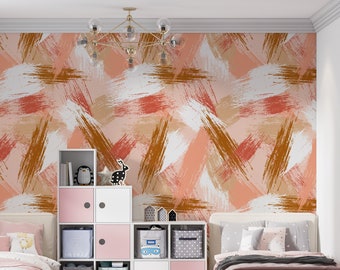 May include: Two twin beds with pink bedding and white pillows in a room with a pink, white, and brown abstract brushstroke wallpaper. A white cube shelf unit with pink and gray storage bins is between the beds.