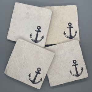 May include: Four beige square coasters with a black anchor design.