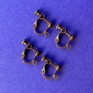 May include: Four antique bronze clip-on earrings. The earrings are made of metal and have a screw-on closure.