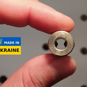 May include: A small, silver metal ring with a ridged exterior and a star-shaped interior opening. The image includes a label that reads "MADE IN UKRAINE" in blue and yellow.