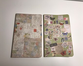 May include: Two notebooks with different designs. The notebook on the left has a vintage newspaper print with faded colors and handwritten text. The notebook on the right has a green cover with various nature-themed stickers, including butterflies, flowers, and mushrooms.
