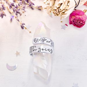 May include: Two silver rings with floral designs. The top ring says "keep" and the bottom ring says "going".