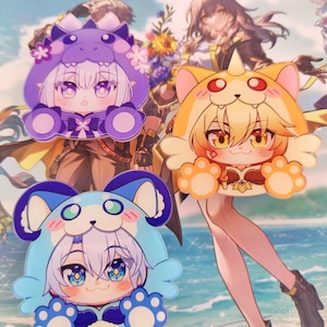 May include: Three anime-style character stickers. One is purple with a dragon-like hood, another is orange with a cat-like hood, and the last is blue with a bear-like hood. Each sticker has large eyes and paw-shaped details.