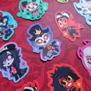 May include: A collection of colorful cartoon character stickers on a red background. The stickers feature various characters with distinct designs, including a jester, a devil, and a wolf. Each sticker has a unique shape and vibrant color scheme, with star-shaped accents.