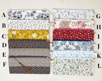 May include: A collection of rectangular pencil cases with zipper closures. The cases feature various floral patterns in colors like white, yellow, red, and blue. Some cases have a tassel attached. The cases are arranged in two columns.