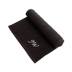 May include: A black rolled up towel with white embroidered initials "J.W."