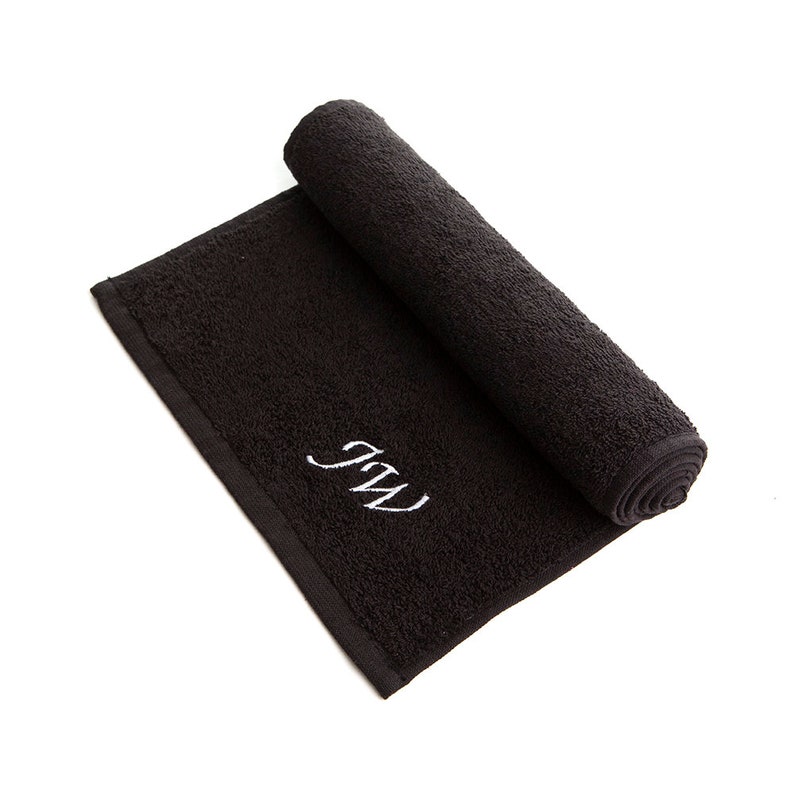 May include: A black rolled up towel with white embroidered initials "J.W."