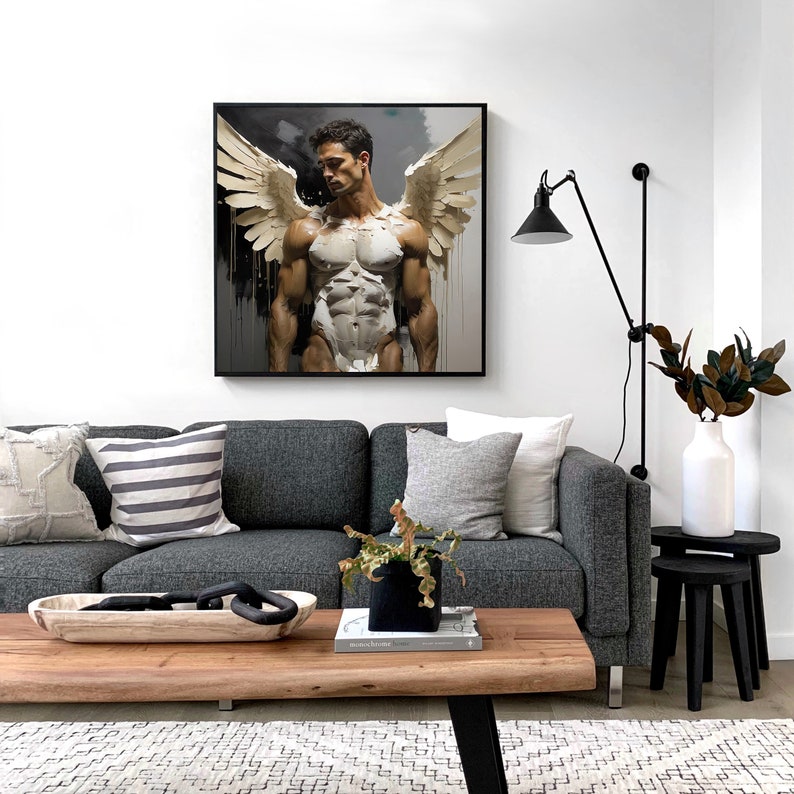 May include: A black framed canvas print of a muscular man with wings. The man is standing with his arms at his sides and looking down. The background is a dark gray with white streaks.