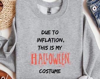 Puede incluir: Una sudadera gris jaspeada con el texto "DUE TO INFLATION, THIS IS MY HALLOWEEN COSTUME" en letras negras y naranjas. La sudadera es de cuello redondo.