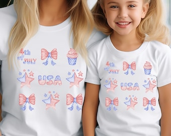 Puede incluir: Camisetas blancas con diseños patrióticos. Las camisetas presentan ilustraciones rojas, blancas y azules de lazos, cupcakes, estrellas y los textos "4th of July" y "USA". Las camisetas son usadas por una mujer y una niña.