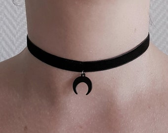 May include: A black velvet choker with a crescent moon pendant.