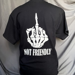 K&ouml;nnte beinhalten: Schwarzes T-Shirt mit einer wei&szlig;en Skeletthand, die den Mittelfinger zeigt, und dem Text "NOT FRIENDLY" auf der R&uuml;ckseite.