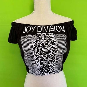 Pode incluir: Top cropped preto de ombros descobertos com um gráfico branco da capa do álbum "Unknown Pleasures" do Joy Division.