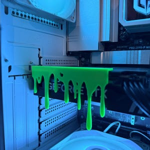 May include: A computer case interior featuring a neon green GPU support bracket with a dripping design. The graphics card displays "GEFORCE RTX". The case includes a white fan and blue lighting, typical of a gaming PC.