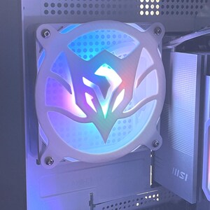 May include: A white computer fan with a central design that glows with a spectrum of colors, including blue, purple, and red. The fan is mounted inside a computer case, with visible components and the text "GEFORCE RTX".