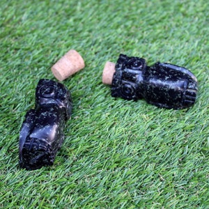 Peut inclure: Deux bouchons de bouteille en forme de hibou noirs et verts avec des bouchons en liège. Les bouchons sont faits d'un matériau ressemblant à de la pierre mouchetée.