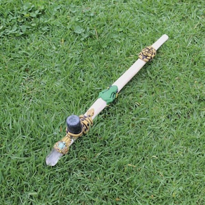 May include: A wooden smoking pipe with a crystal tip, a green frog, and a snake design. The pipe is decorated with yellow and black accents.