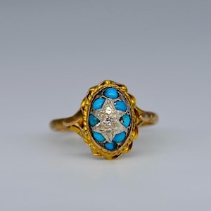 Puede incluir: Un anillo de oro con un diseño de estrella de turquesa y diamante. El anillo está engastado en forma ovalada y tiene un delicado diseño de filigrana.
