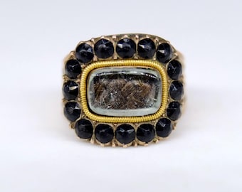 Ein fabelhafter georgianischer Trauerring, die zentrale Tafel aus natürlichem Haar, umgeben von facettierten Jet-Steinen, 15 Karat Gold um 1829