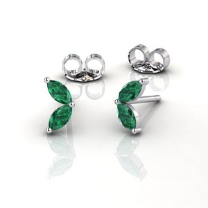 Puede incluir: Un par de pendientes de plata con dos piedras preciosas de color verde esmeralda en forma de marquesa engastadas en cada pendiente.