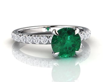 May include: A silver ring featuring a large emerald green gemstone set in a band of small diamonds.
