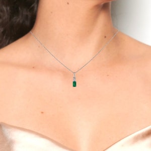 May include: A silver chain necklace with a small emerald green pendant.
