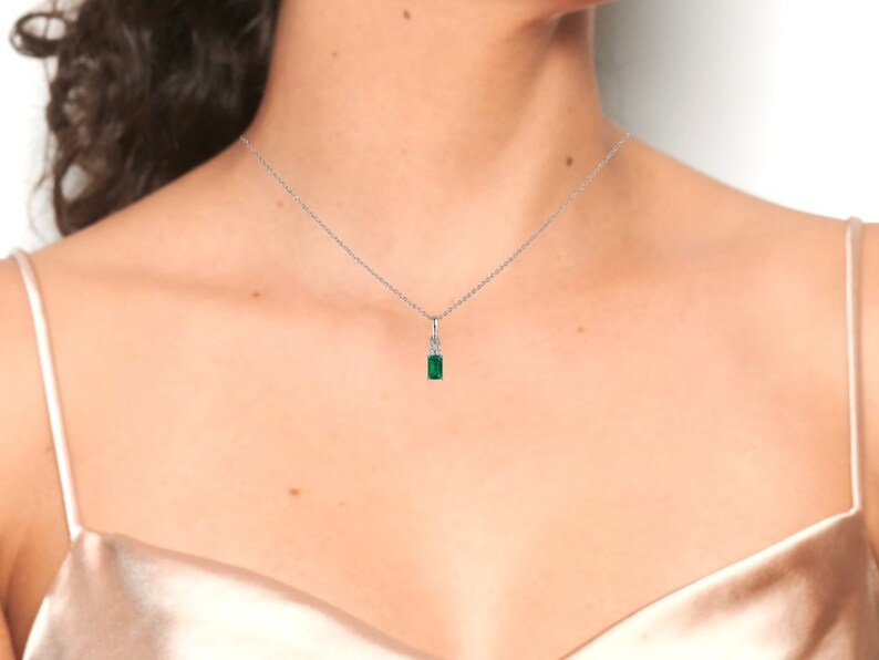 May include: A silver chain necklace with a small emerald green pendant.