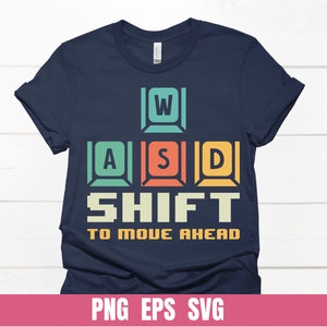 May include: A navy blue t-shirt with a graphic of retro-style keyboard keys spelling out "W, A, S, D, SHIFT to move ahead".