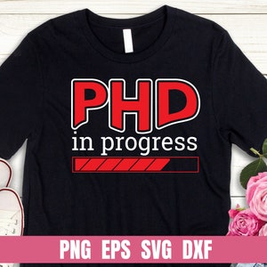以下が含まれることがあります： 赤い文字で「PhD in progress」と書かれた黒いTシャツ。その下に赤いプログレスバーがあります。