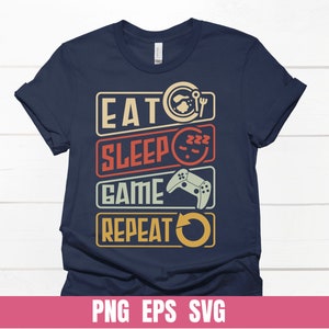 Könnte beinhalten: Ein marineblaues T-Shirt mit einer Retro-Grafik, auf der "Essen Schlafen Spielen Wiederholen" steht, mit Symbolen für einen Teller, ein schlafendes Gesicht, einen Videospiel-Controller und einen Kreispfeil.