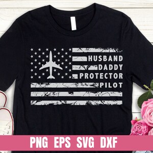 May include: Black t-shirt with a distressed American flag design and the text "Husband Daddy Protector Pilot".