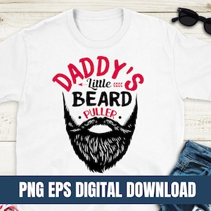 May include: White t-shirt with a black and white illustration of a beard and the text "Daddy's Little Beard Puller".