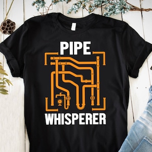 May include: Black t-shirt with a white graphic of a pipe system and the text "PIPE WHISPERER".