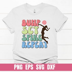 Könnte beinhalten: Weißes T-Shirt mit dem Text "Bump Set Spike Repeat" in bunten, Retro-Lettern. In der Mitte des Textes befindet sich eine Silhouette eines Volleyballspielers, der den Ball attackiert.