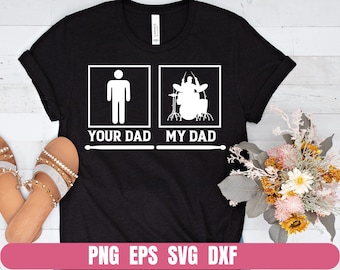 Puede incluir: Camiseta negra con texto blanco que dice "Your Dad" y "My Dad". El lado derecho de la camiseta presenta una silueta de una persona tocando la batería.