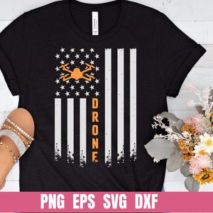 May include: A black t-shirt with a distressed American flag design and a drone graphic. The text "DRONE" is vertically aligned on the right side of the flag.