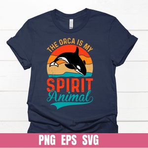 May include: A navy blue t-shirt with a retro-style graphic of an orca whale jumping through a sunset. The text "The Orca is my Spirit Animal" is printed on the shirt.