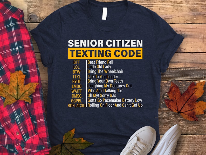 May include: A navy blue t-shirt with a white graphic that says "Senior Citizen Texting Code" and lists common texting abbreviations and their meanings for older adults.
