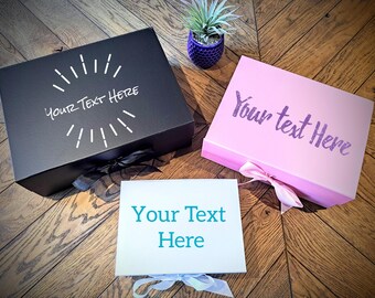 May include: Three gift boxes with different colored lids and ribbons. The black box has white text that says "Your Text Here" with a sunburst design. The pink box has purple text that says "Your Text Here". The white box has teal text that says "Your Text Here".
