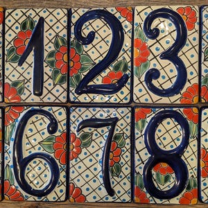 May include: Ten ceramic tiles with blue numbers 1 through 9 and 0 on a white background with a blue and white checkered pattern and red, green, and yellow floral designs.