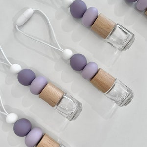May include: Five purple and white beaded car air fresheners with wooden caps and clear glass bottles. The beads are ombre and the string is white.