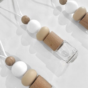 May include: Three car air fresheners with wooden beads and a clear glass bottle. The beads are white, brown and beige.