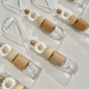 May include: Set of six car air fresheners with a daisy charm, wooden beads, and a clear glass bottle. Each air freshener has a white string for hanging.