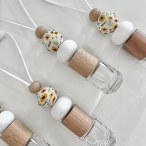 May include: Four car air fresheners with floral patterned beads, white beads, wooden beads, and clear glass bottles. The air fresheners are attached to white strings.