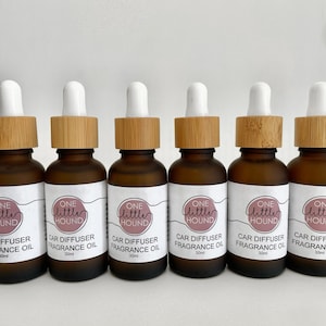 May include: Six amber glass bottles with white droppers and bamboo caps. Each bottle contains a car diffuser fragrance oil and is labelled "One Little Hound Car Diffuser Fragrance Oil 30ml".