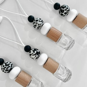 May include: Four car air fresheners with black and white patterned beads, white beads, and wooden caps. The fresheners are attached to strings.