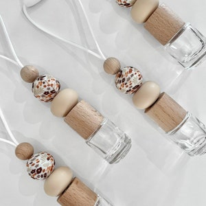 May include: Four car air fresheners with floral fabric beads, wooden beads, and clear glass bottles. The air fresheners are hanging from white cords.