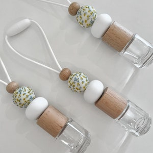 May include: Three white and wood car air fresheners with a floral pattern. Each air freshener has a white string for hanging.