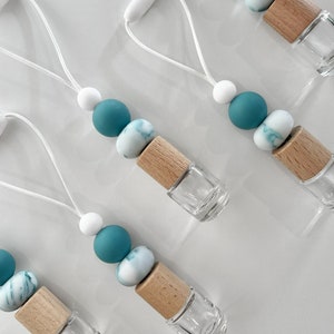 May include: Four teal and white beaded car air fresheners with a wooden cap and a clear glass bottle. Each air freshener has a white string loop for hanging.